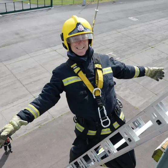 Harnessed firefighter up a ladder