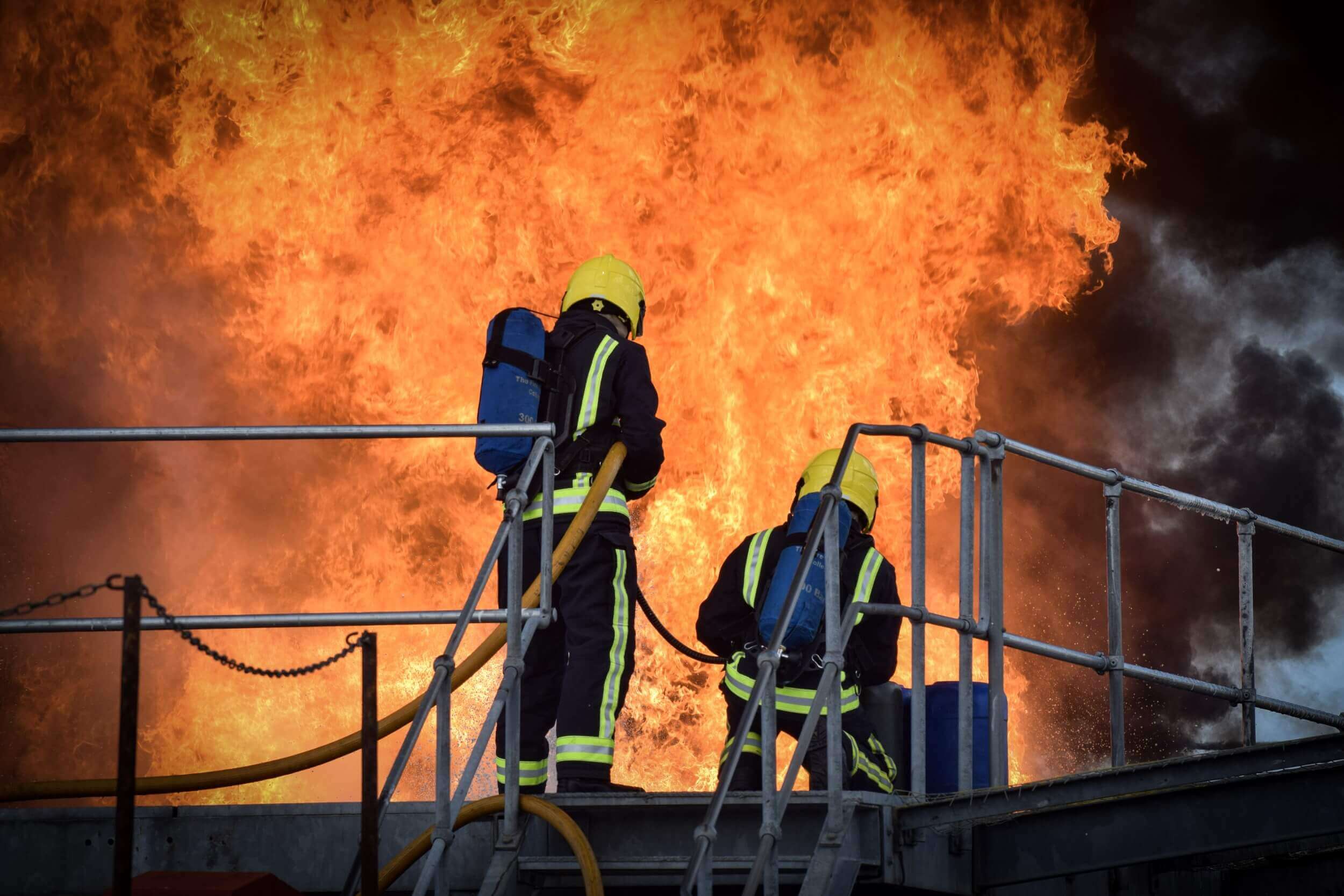 Firefighter trainees tackling large fire with fire hose