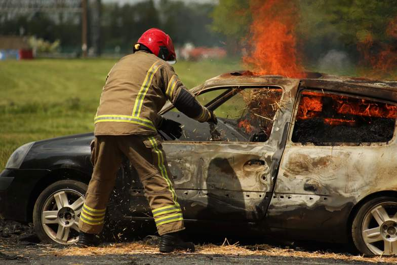 Trainee firefighter attending to flaming car