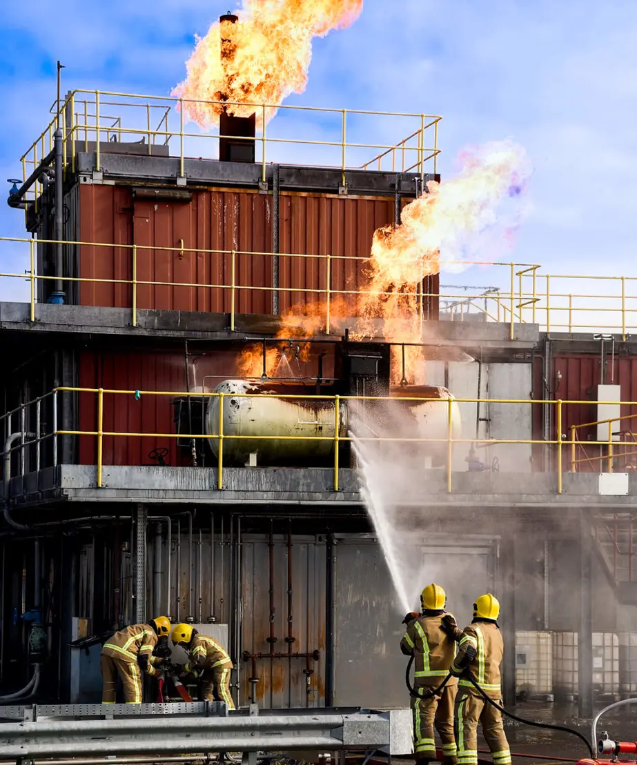 Trainee firefighters dousing a burning building with a fire hose